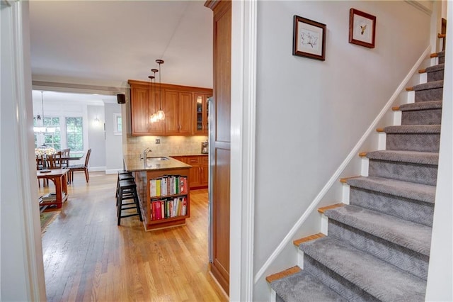stairs featuring baseboards, a chandelier, and wood finished floors