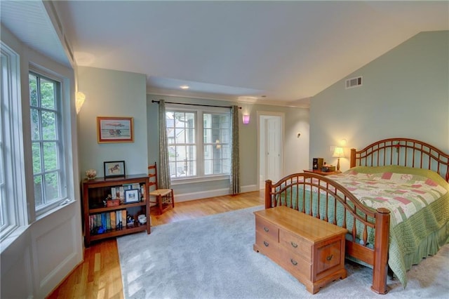 bedroom featuring visible vents, baseboards, wood finished floors, and vaulted ceiling