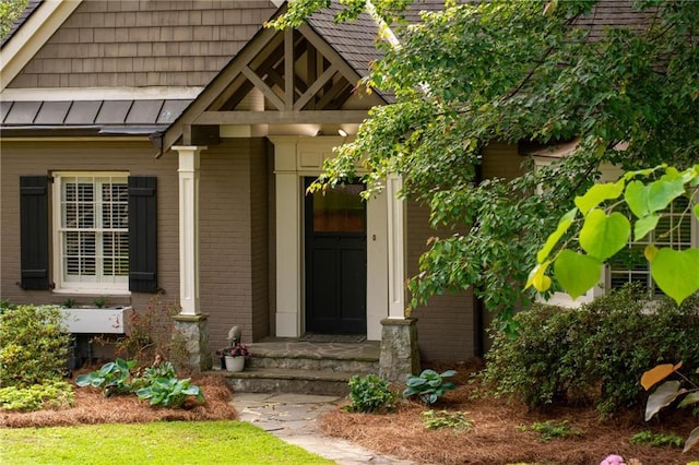 entrance to property featuring brick siding, a standing seam roof, and metal roof
