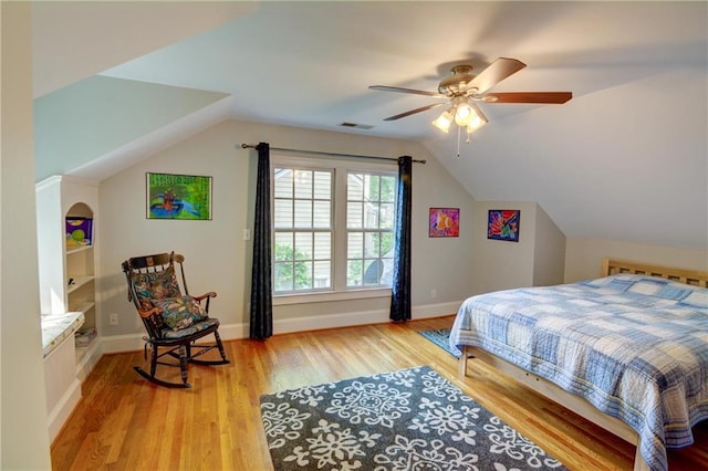 bedroom with visible vents, wood finished floors, baseboards, ceiling fan, and vaulted ceiling