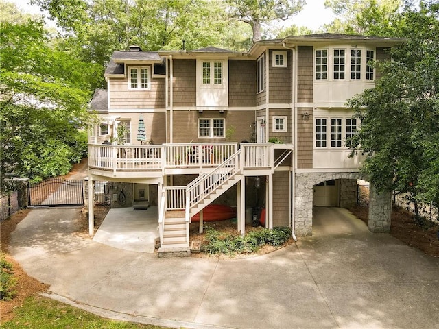 rear view of house featuring driveway, a chimney, a gate, a carport, and stairs