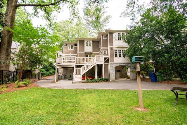 rear view of house with a wooden deck, stairway, fence, a yard, and stone siding