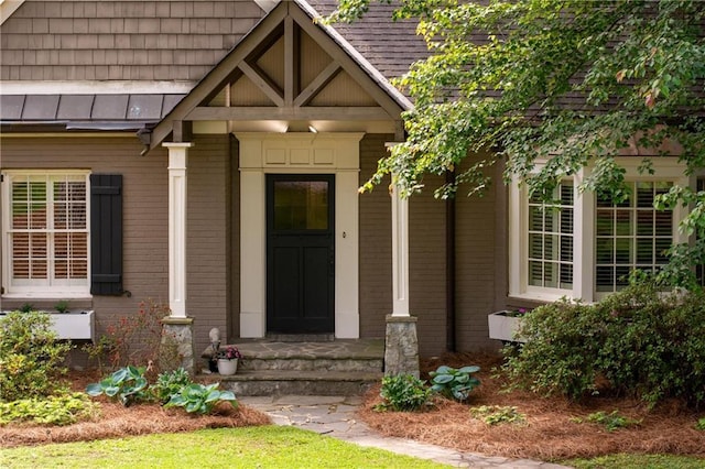 entrance to property with brick siding and a standing seam roof