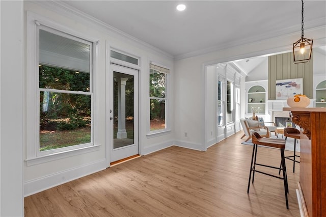 doorway with built in features, baseboards, light wood-style flooring, ornamental molding, and a fireplace