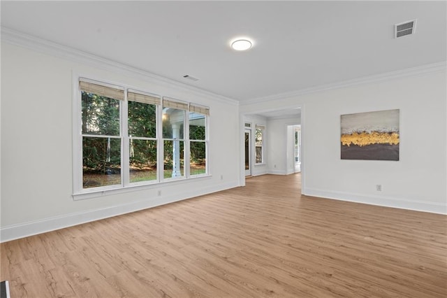 spare room featuring ornamental molding, visible vents, light wood-style flooring, and baseboards