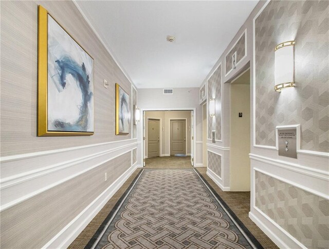 195 14th St NE Unit 303, Atlanta, GA 30309 - hallway with a decorative wall, dark colored carpet, a wainscoted wall, and wallpapered walls