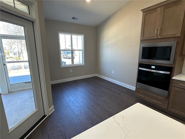 kitchen featuring oven, dark wood-style flooring, baseboards, light countertops, and built in microwave