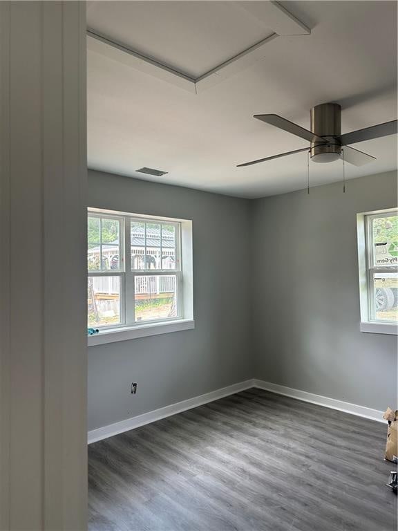 empty room featuring a wealth of natural light, dark wood-type flooring, and ceiling fan