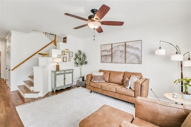 living area featuring ceiling fan, stairway, wood finished floors, and ornamental molding