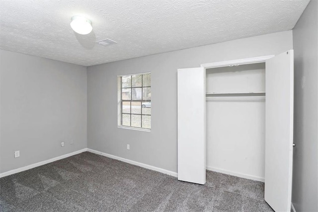 unfurnished bedroom featuring carpet, a textured ceiling, and a closet