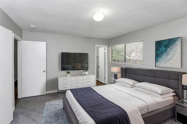 bedroom with dark carpet and a textured ceiling