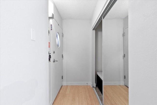 hallway featuring light hardwood / wood-style flooring and a textured ceiling