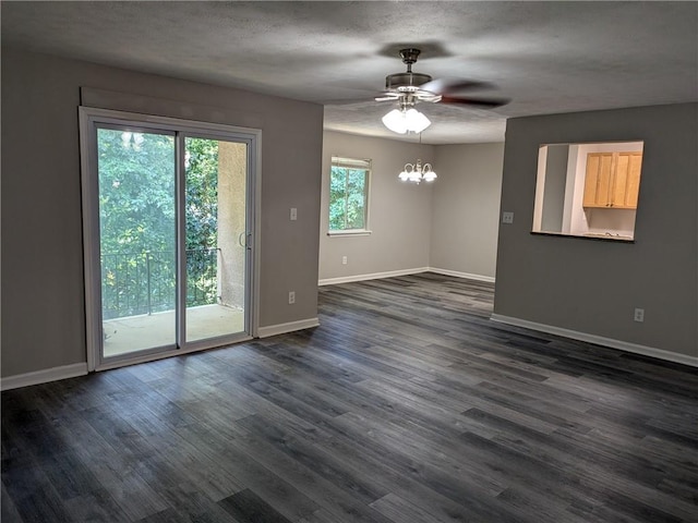 empty room featuring ceiling fan with notable chandelier, dark hardwood / wood-style flooring, and a textured ceiling