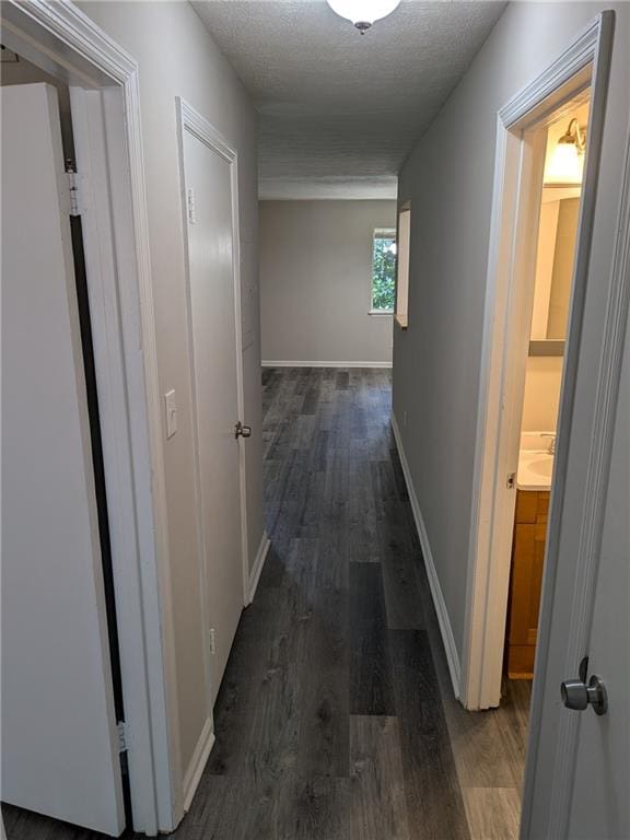 corridor with a textured ceiling and dark wood-type flooring