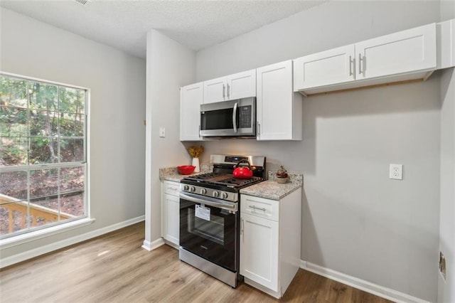 kitchen featuring plenty of natural light, white cabinetry, and stainless steel appliances