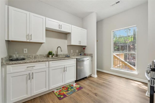 kitchen with light stone countertops, light wood-type flooring, stainless steel appliances, sink, and white cabinetry