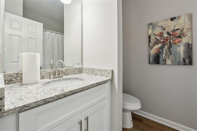 bathroom with toilet, vanity, and hardwood / wood-style flooring