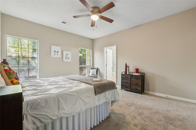 bedroom featuring connected bathroom, multiple windows, ceiling fan, and light colored carpet