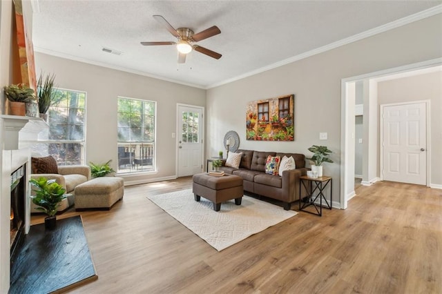 living room with crown molding, light hardwood / wood-style flooring, and ceiling fan