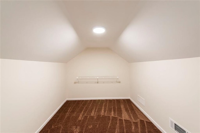 bonus room with dark colored carpet and lofted ceiling