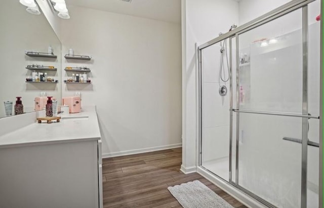 bathroom with wood-type flooring, vanity, and a shower with door