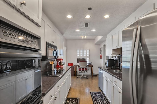 kitchen featuring light wood-type flooring, black appliances, white cabinetry, and a textured ceiling