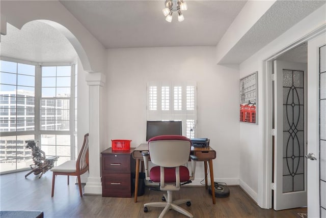 office area with arched walkways, a healthy amount of sunlight, and wood finished floors