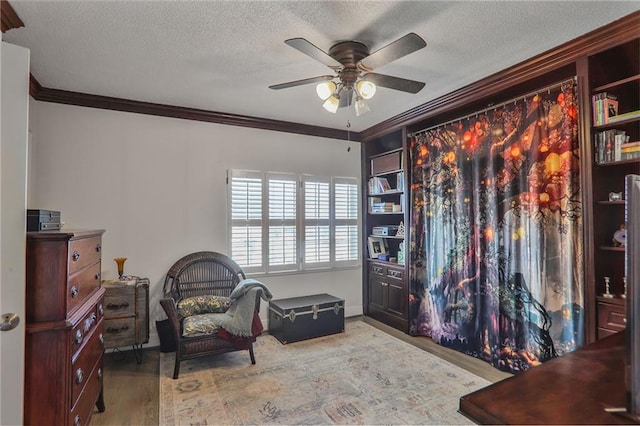 living area featuring a textured ceiling, ornamental molding, wood finished floors, and a ceiling fan