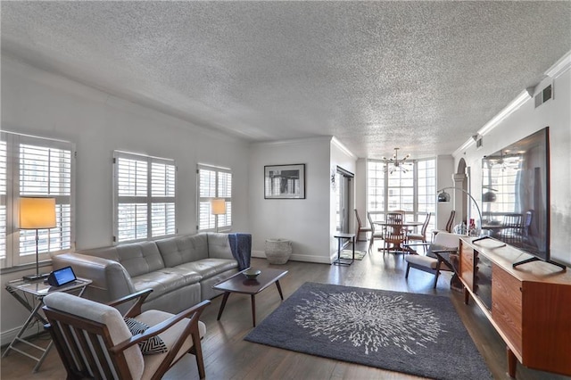 living area featuring a chandelier, wood finished floors, visible vents, baseboards, and ornamental molding