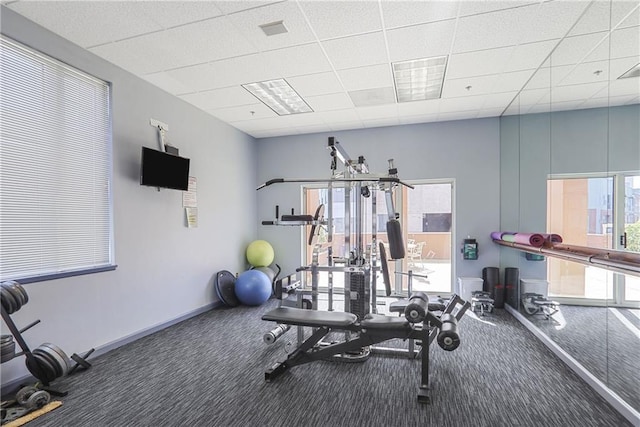 exercise area with a paneled ceiling, carpet flooring, visible vents, and baseboards