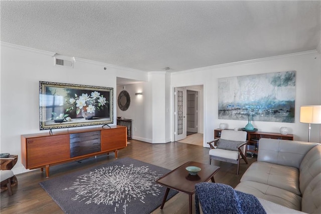 living room with a textured ceiling, wood finished floors, visible vents, and crown molding