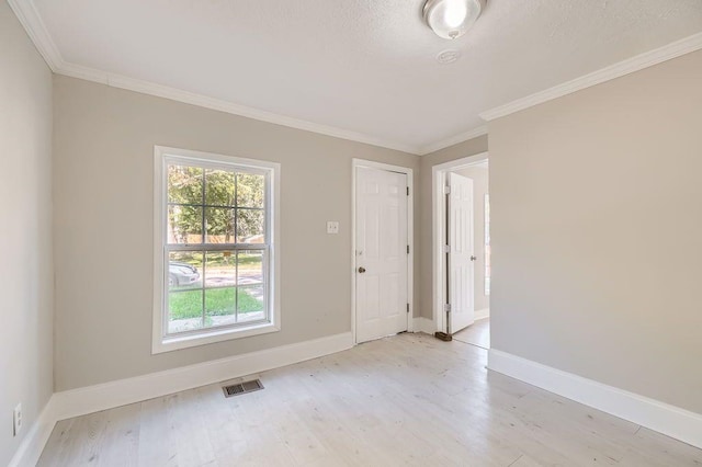 interior space with crown molding, baseboards, visible vents, and light wood-type flooring