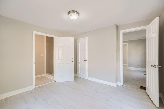 unfurnished bedroom with baseboards, a closet, and light wood-style flooring