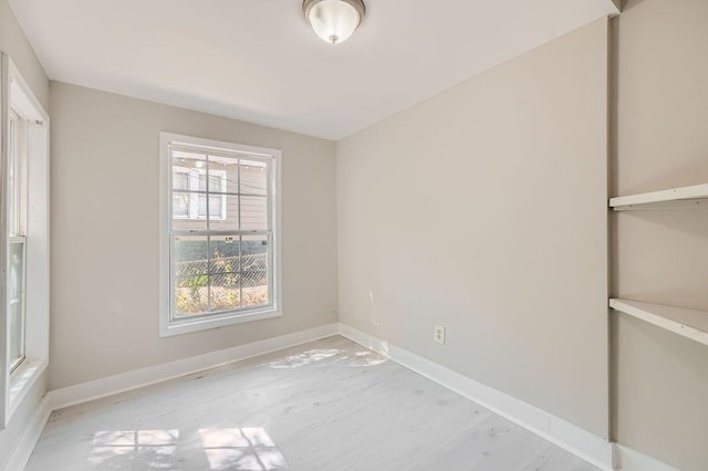 spare room featuring baseboards and light wood-style floors
