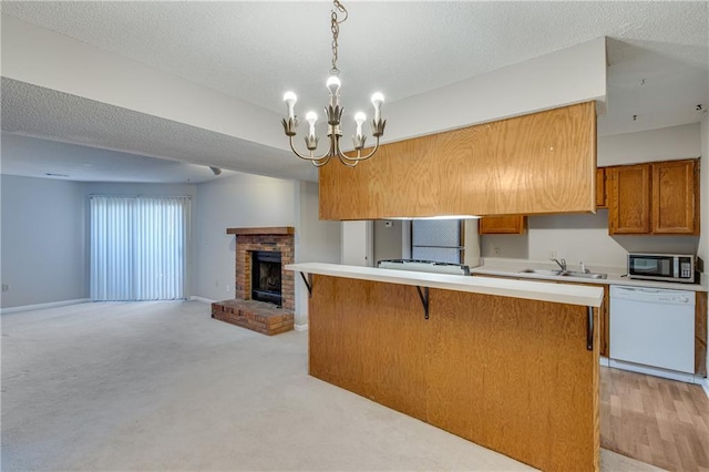 kitchen with pendant lighting, a fireplace, sink, white dishwasher, and a textured ceiling