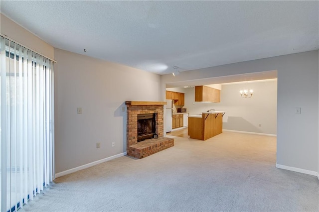 unfurnished living room featuring a chandelier, light carpet, a textured ceiling, and a fireplace