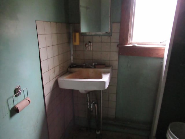 bathroom featuring toilet, sink, and tile walls