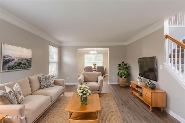 living room featuring stairway, ornamental molding, wood finished floors, baseboards, and a chandelier