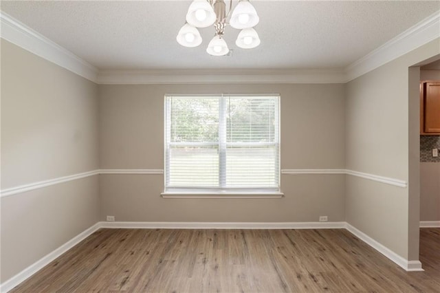 unfurnished room with a chandelier, light wood-style flooring, crown molding, a textured ceiling, and baseboards