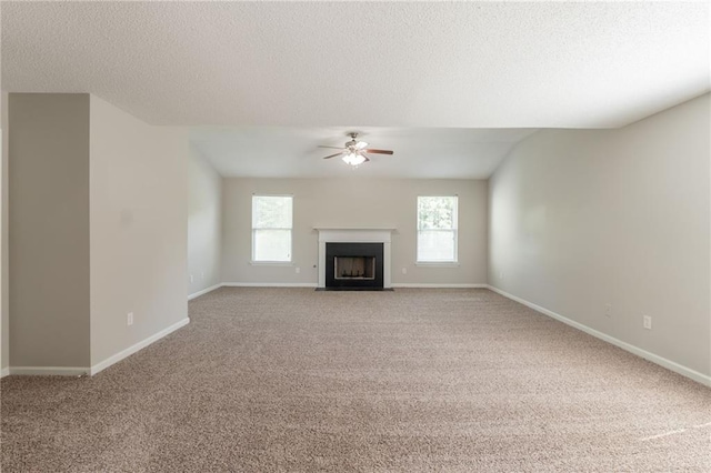 unfurnished living room with a ceiling fan, light carpet, a textured ceiling, and baseboards
