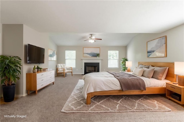 bedroom with light carpet, ceiling fan, baseboards, vaulted ceiling, and a fireplace