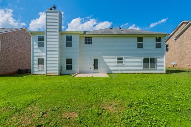 rear view of property featuring a patio area, a yard, and a chimney