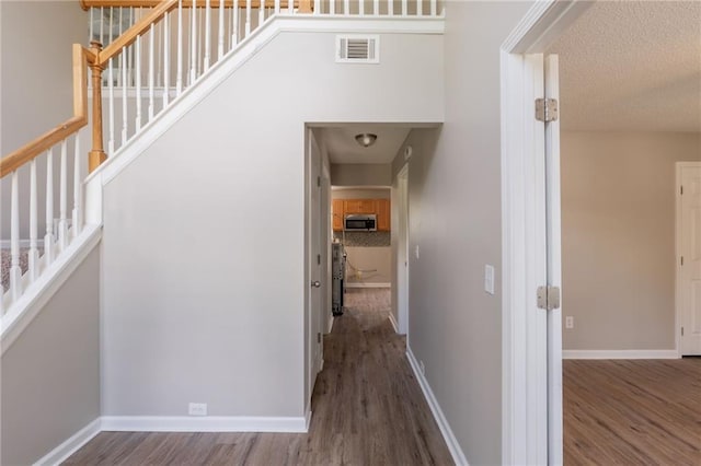 corridor with wood finished floors, stairway, and baseboards