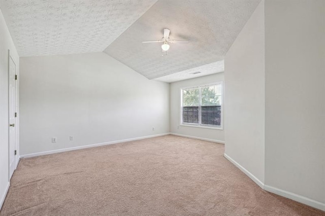 spare room featuring a textured ceiling, ceiling fan, light carpet, and vaulted ceiling