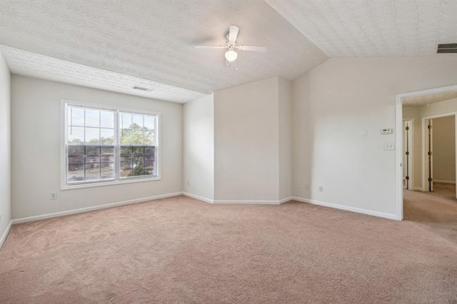 empty room with light carpet, a textured ceiling, ceiling fan, and lofted ceiling