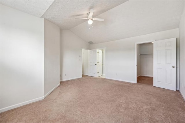 unfurnished bedroom featuring a textured ceiling, vaulted ceiling, ceiling fan, carpet floors, and a closet