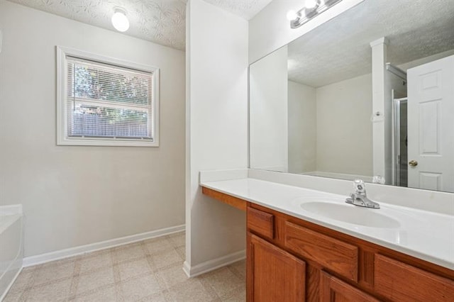 bathroom with vanity, a textured ceiling, and a tub