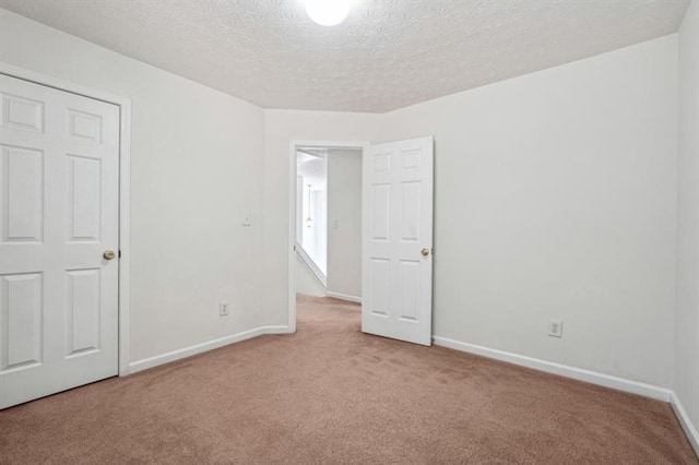 spare room featuring light colored carpet and a textured ceiling