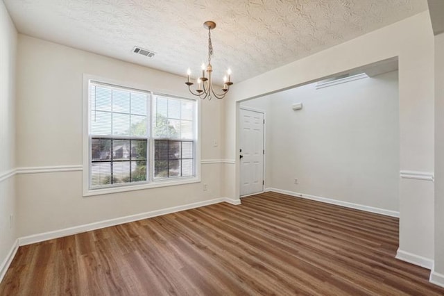 spare room with dark hardwood / wood-style flooring, a chandelier, and a textured ceiling