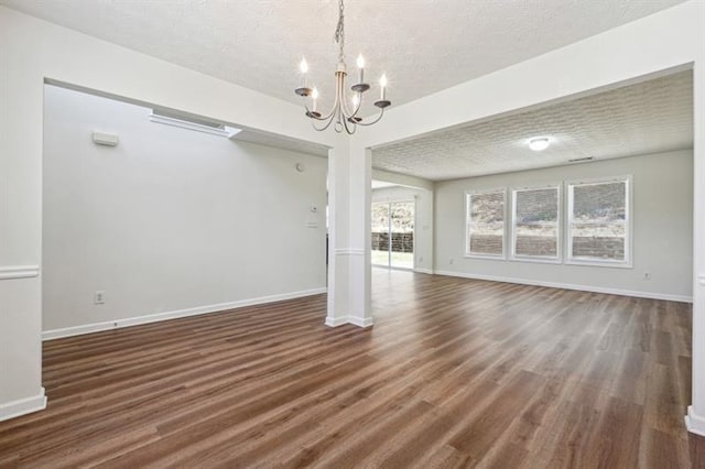 unfurnished living room featuring dark wood-type flooring, a textured ceiling, and a notable chandelier